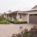 A Better Driveway A suburban house with a beige facade, large driveway, and surrounding gardens.