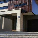 A popular exposed blend from one of our suppliers Exterior view of a modern two-story building with wooden paneling and a pebble driveway.