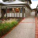 Standard exposed aggregate with 10% bluestone added Suburban house with a grey and white exterior, porch, and concrete driveway bordered by red bricks.