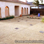 Placing decorative outdoor tiles with your exposed aggregate is easy Residential driveway with exposed aggregate concrete and landscaped garden.