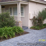 Charming abstract design Suburban house with a gray stone driveway and garden beds.