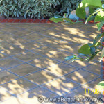 The perfect outdoor sitting area A tiled patio with shadows from nearby plants, bordered by red bricks.