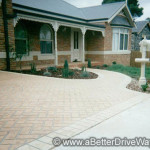 A light coloured driveway in herringbone design Brick house with a herringbone-patterned driveway and landscaped front yard.