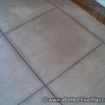 A clever and inexpensive way to create 'tiles' on your verandah A tiled floor with beige tiles, outlined by dark lines. A brick wall is partially visible in the upper corner.